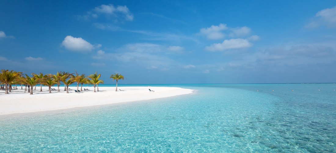 Unberührter weißer Sandstrand mit Palmen und türkisblauem Meer auf den Malediven