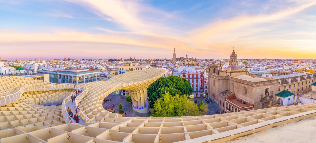 Panoramablick auf Sevilla bei Sonnenuntergang mit dem modernen Holzdach Metropol Parasol im Vordergrund und der Altstadt im Hintergrund.