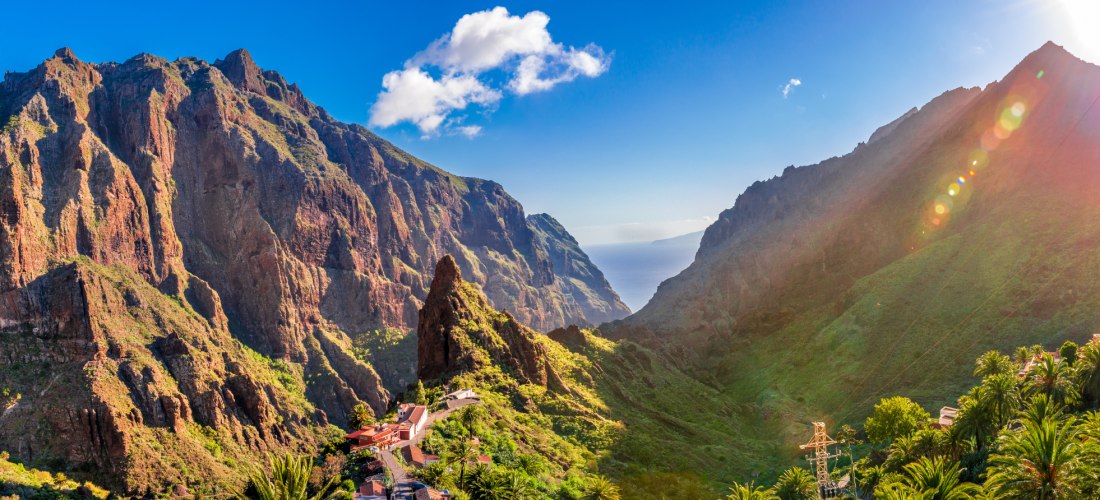 Panoramablick auf die Masca-Schlucht auf Teneriffa mit steilen Felsen, grüner Vegetation und Sonnenstrahlen