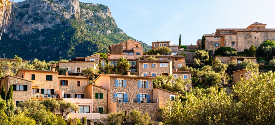 Blick auf das Bergdorf Deià auf Mallorca mit traditionellen Steinhäusern, Olivenhainen und der Serra de Tramuntana im Hintergrund