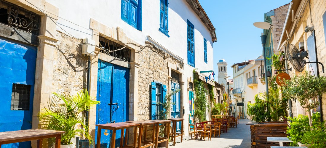 Enge Altstadtgasse in Limassol mit traditionellen Steinhäusern, blauen Türen und gemütlichen Straßencafés