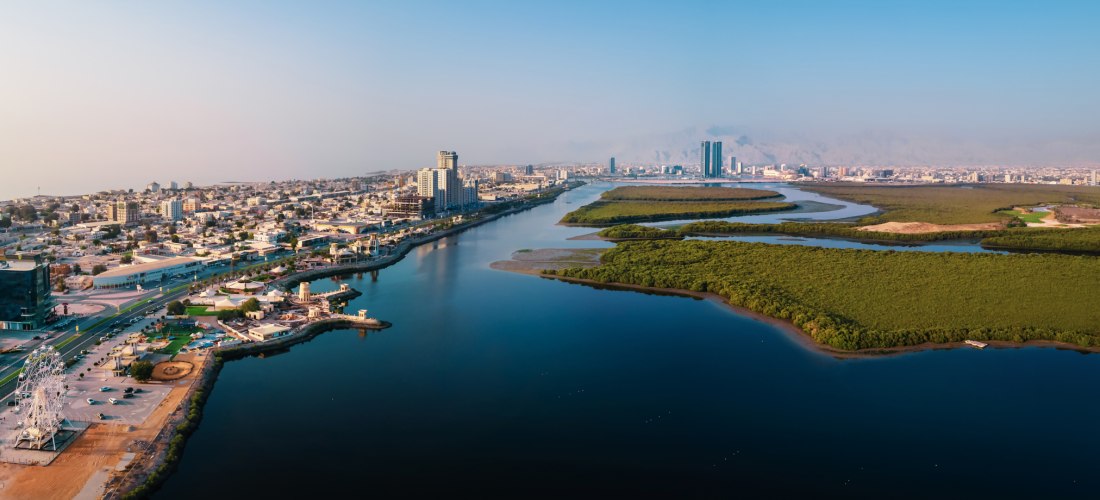 Luftaufnahme der Skyline von Ras Al Khaimah mit Mangroven, Wasserkanälen und moderner Corniche.