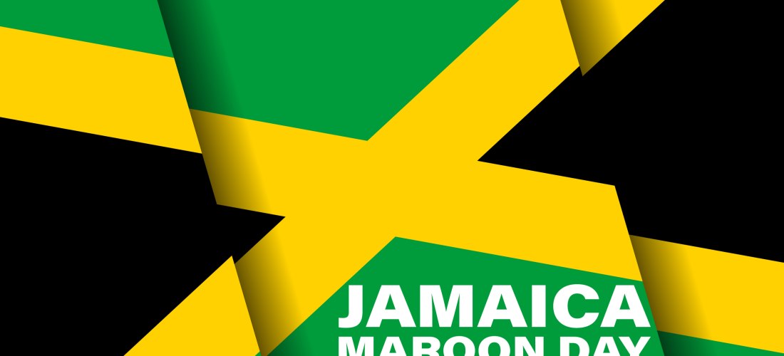 Grafik mit der jamaikanischen Flagge im Hintergrund. In der unteren rechten Ecke steht in weißer Schrift: 'Jamaica Maroon Day – January 6'. Die Flagge zeigt ein gelbes Kreuz, das in vier Dreiecke unterteilt: zwei grüne oben links und unten rechts, sowie z