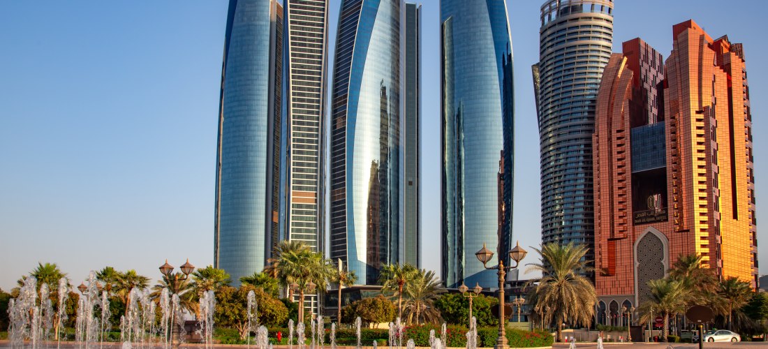 Die markanten, modernen Wolkenkratzer der Etihad Towers in Abu Dhabi, umgeben von Wasserfontänen und Palmen