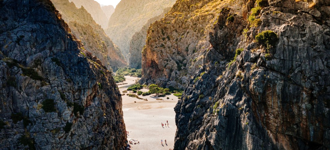 Schlucht Torrent de Pareis auf Mallorca mit kleinem Strand zwischen hohen Felswänden und Badegästen
