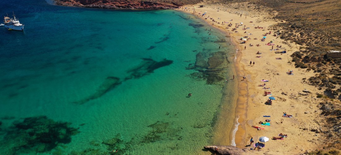 Agios Sostis Beach auf Mykonos mit goldenem Sandstrand, türkisfarbenem Wasser und entspannter, naturbelassener Atmosphäre