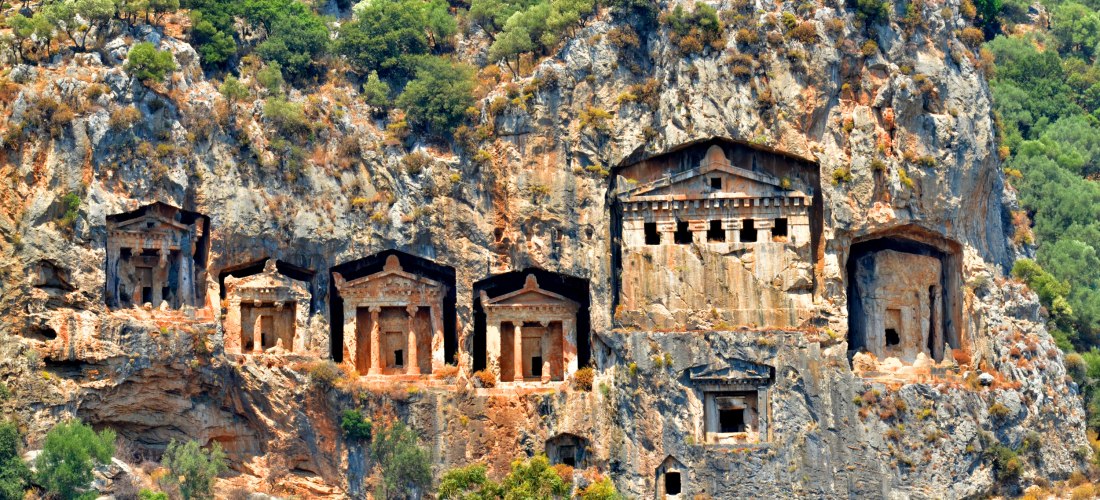 Antike lykische Felsengräber in Fethiye, in den Felsen geschlagene Tempelruinen, umgeben von grüner Vegetation