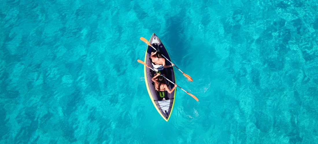 2 Menschen im Paddelboot auf dem Meer, von oben fotografiert