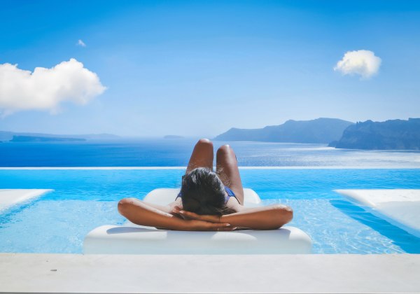 eine Frau in den Ferien auf Santorini entspannen in einem Swimmingpool mit Blick auf das Caldera-Meer 