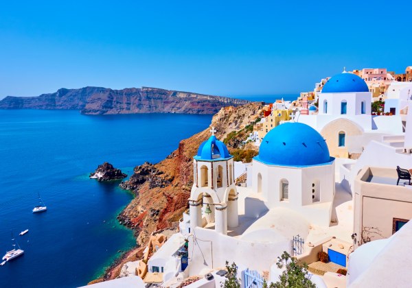 Blick auf weiß - blaue Häuser auf einem Berg in Santorini mit Blick auf das Meer