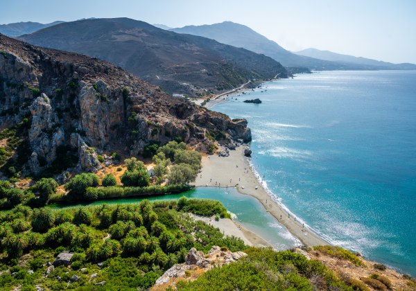 Palmenstrand mit Bergen und Meer im Hintergrund