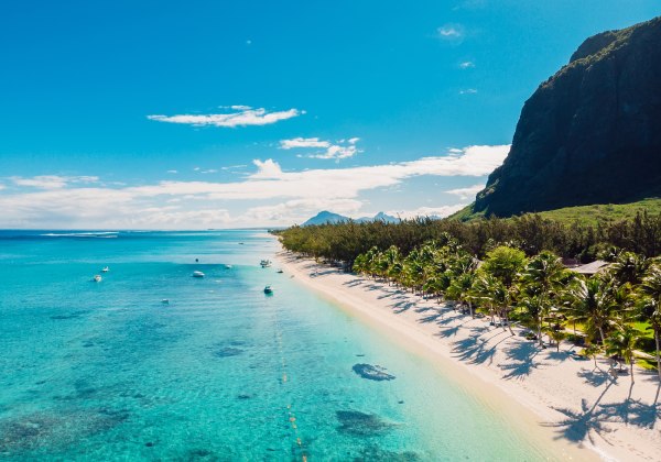 Ein paradiesisches Reiseziel: Feinster Sand, sanftes Meeresrauschen und majestätische Berge im Hintergrund – der perfekte Ort zum Träumen und Entspannen.