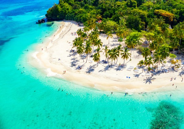 Luftaufnahme einer Palmeninsel mit weißem Sandstrand und türkisblauem Meer