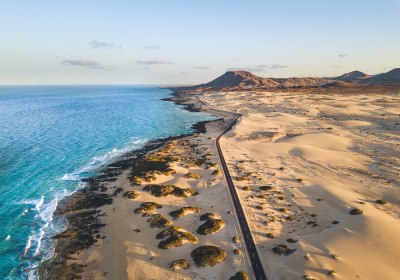 Sanddünen und Küste auf den Kanaren mit Straße und vulkanischen Hügeln
