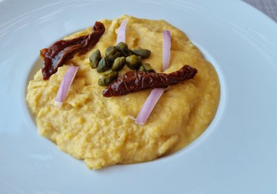 Traditionelles griechisches Fava-Püree mit Kapern, roten Zwiebeln und getrockneten Tomaten