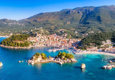 Blick auf eine griechische Küstenstadt mit Hafen und Berglandschaft