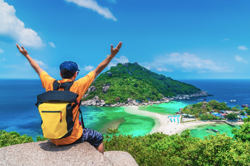 Aussicht auf tropische Insel mit Wanderer Mann mit Rucksack genießt die Aussicht auf eine tropische Insel mit weißem Sandstrand und türkisblauem Wasser in Costa Rica