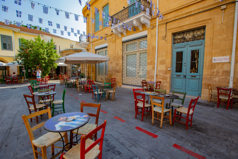 Altstadt von Nikosia: gemütlicher Platz mit Straßencafé, bunten Stühlen, Sandsteinfassaden und Wimpelketten.