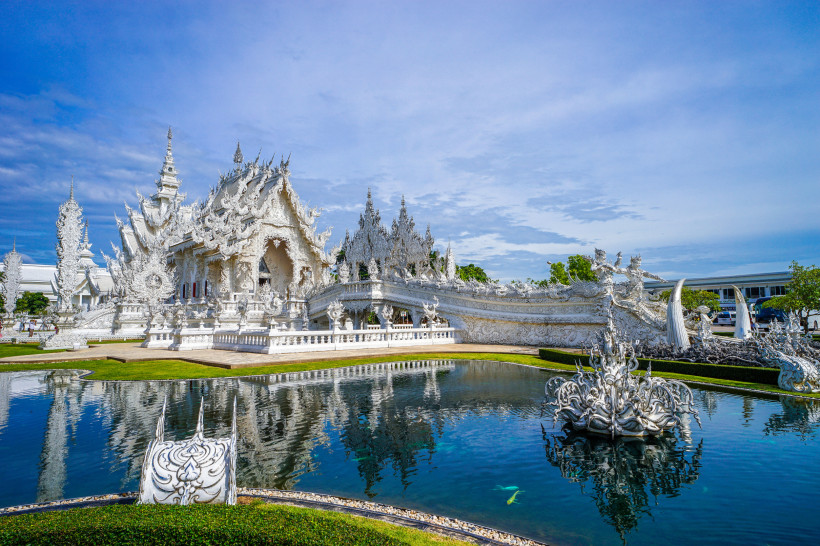 Weißer Tempel Chiang Rai – Wat Rong Khun Thailand | Highlight 2025/2026 Weißer Tempel Wat Rong Khun in Chiang Rai, Thailand – beeindruckende weiße Architektur mit Spiegelornamenten und Teich unter blauem Himmel.
