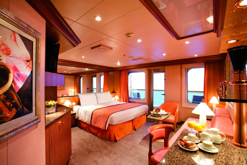 Costa Pacifica – Suite mit Doppelbett, Sitzbereich und Meerblick Suite auf der Costa Pacifica mit Doppelbett, Sitzbereich und Meerblick durch Bullaugenfenster