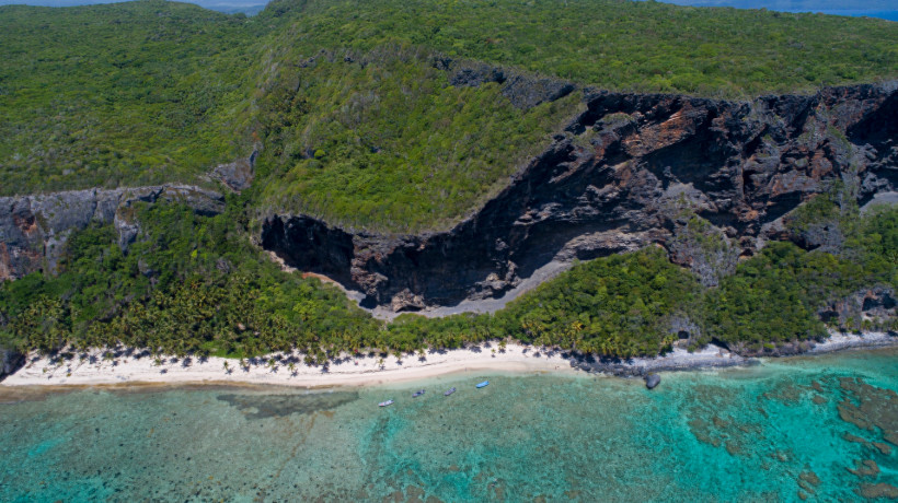 Dominikanische Republik - Playa Frontón Drohnenaufnahme der Steilküste Los Haitises mit dem Playa Frontón in der Dominikanischen Republik mit dichter grüner Vegetation, dunklen Felsformationen, weißem Sandstrand und türkisblauem Wasser