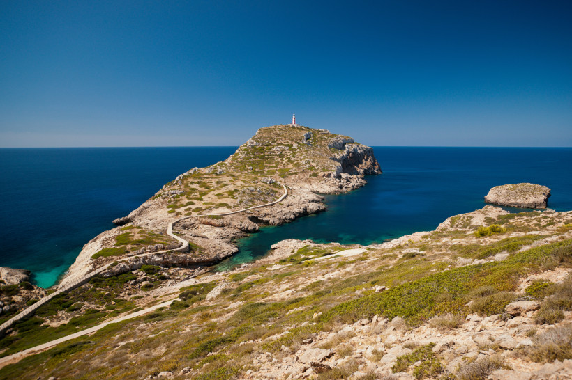 Kap Cabrera: Küstenlandschaft mit Leuchtturm und schmalem Weg entlang der Felsen Halbinsel mit Leuchtturm am Kap Cabrera, umgeben von blauem Meer