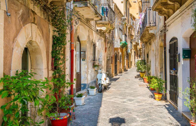 Ortigia Altstadt – charmante Gassen und mediterranes Flair in Syrakus Enge Gasse in der Altstadt von Ortigia, Syrakus, mit Vespa, Blumen und historischen Fassaden – typisch sizilianisches Stadtbild mit mediterranem Charme