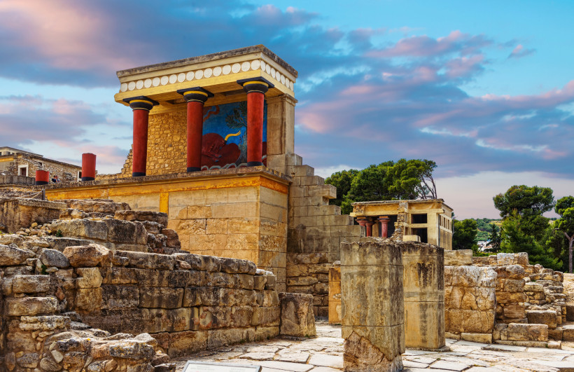 Rekonstruktion am Palast von Knossos bei Heraklion mit roten Säulen und Wandmalerei über antiken Steinmauern