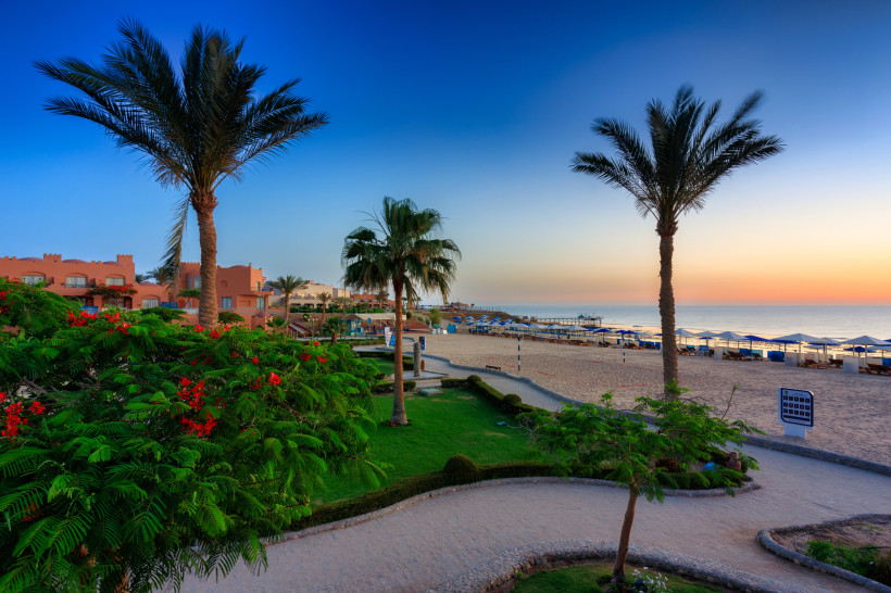 Blick auf den Strand von Marsa Alam mit Palmen, Sonnenliegen und Abendhimmel