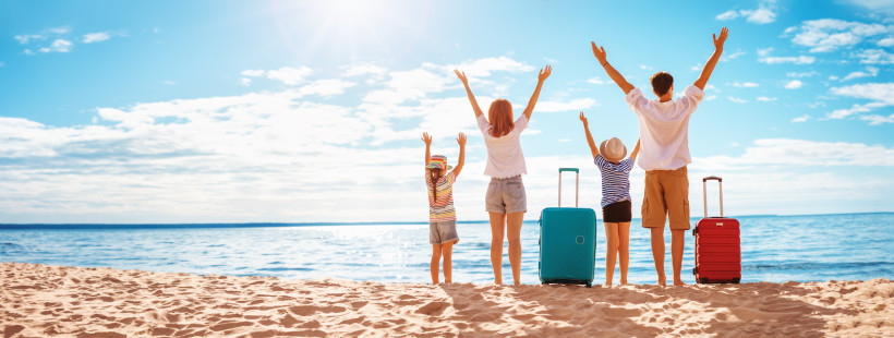 Familie mit Kindern am Sandstrand und Koffer – Start in einen entspannten Familienurlaub am Meer