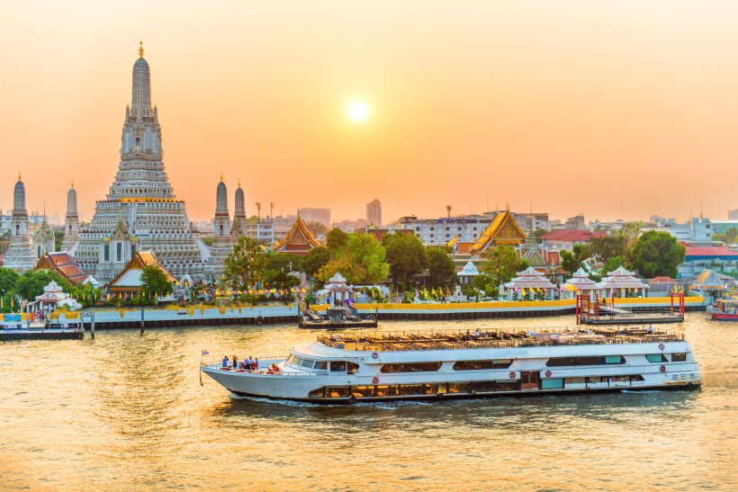 Wat Arun am Chao Phraya bei Sonnenuntergang – Tempel und Flusskreuzfahrt in Bangkok Wat Arun Tempel in Bangkok am Chao Phraya Fluss bei Sonnenuntergang mit Touristenboot im Vordergrund
