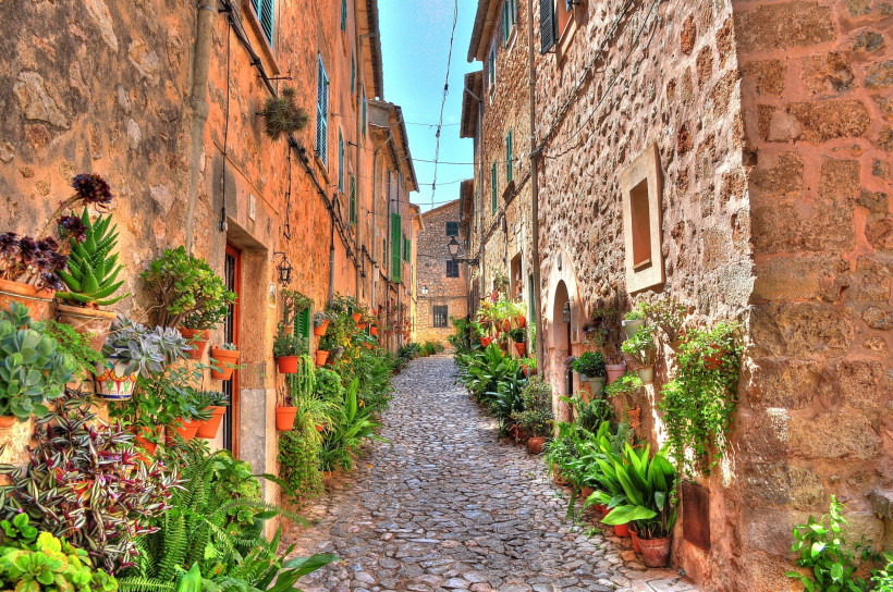 Valldemossa, Mallorca Malerische Gasse in Valldemossa auf Mallorca mit Kopfsteinpflaster, historischen Steinhäusern und vielen Blumentöpfen an den Fassaden