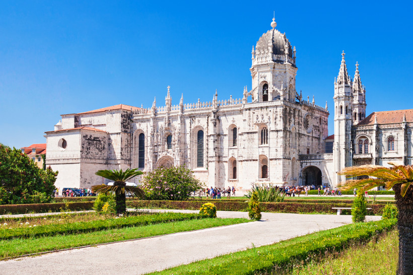 Außenansicht des Mosteiro dos Jerónimos in Lissabon mit Gartenanlage im Vordergrund