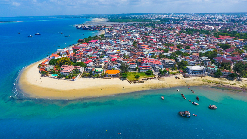 Sansibar Panorama der Halbinsel von Stone Town, Sansibar: sandige Ufer, rote Dächer der UNESCO-Altstadt und zahlreiche Boote im türkisblauen Wasser