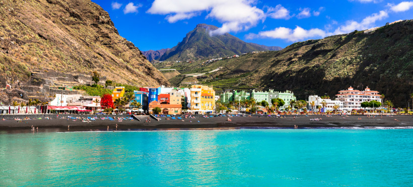 Blick auf Puerto de Tazacorte auf La Palma mit schwarzem Sandstrand, bunten Gebäuden und Bergen im Hintergrund