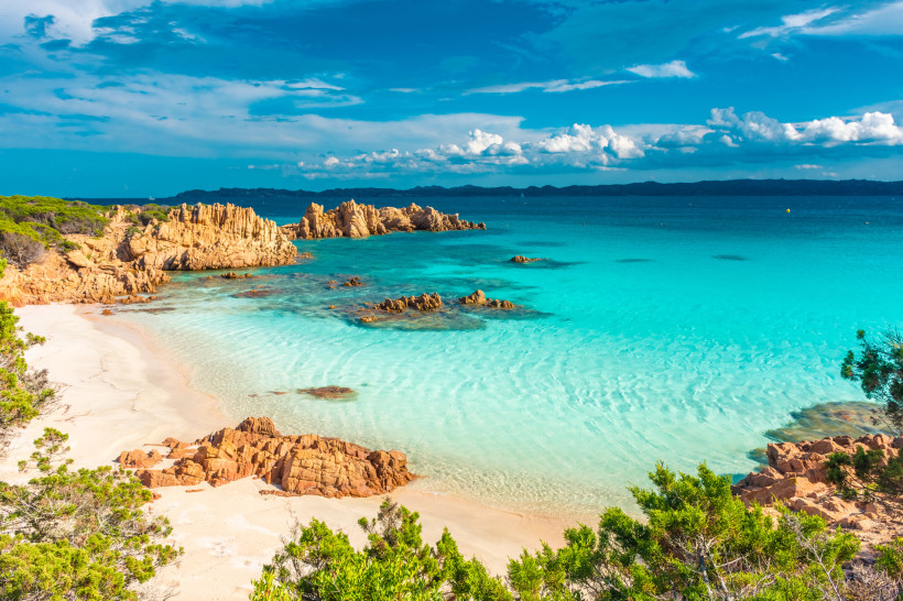 Bucht auf Sardinien mit türkisfarbenem Wasser, Sandstrand und Felsen
