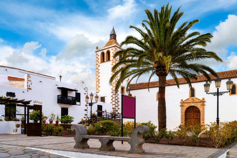 Kirche und Dorfplatz in Betancuria auf Fuerteventura mit Palmenbaum und weiß getünchten Gebäuden