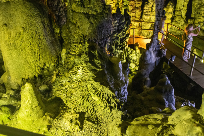 Beleuchtete Tropfsteinformationen in der Dikteon-Höhle mit Steg und Geländer