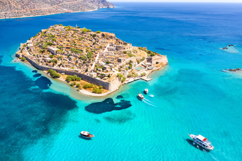 Luftaufnahme der Insel Spinalonga mit Festungsanlagen und Ruinen im türkisblauen Meer