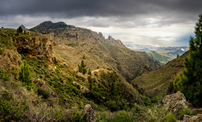Ifonche bei Adeje: Berglandschaft mit Schlucht und Blick Richtung Küste Blick vom Aussichtspunkt Ifonche bei Adeje über ein bergiges Tal mit Felsformationen und Vegetation unter dunklen Wolken