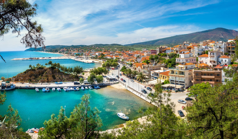 Blick auf eine Küstenstadt auf Thassos mit Hafenbecken, Booten und Häusern mit roten Dächern