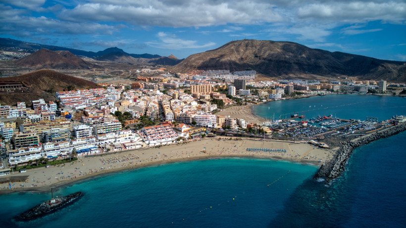 Blick auf den Hafen von Los Cristianos mit Marina, Strand und Küstenstadt vor bergiger Landschaft