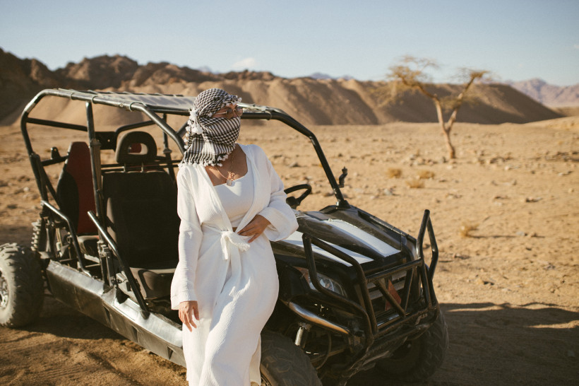 Ägypten Safari Frau vor einem Buggy in der Wüste, im Hintergrund sind Berge