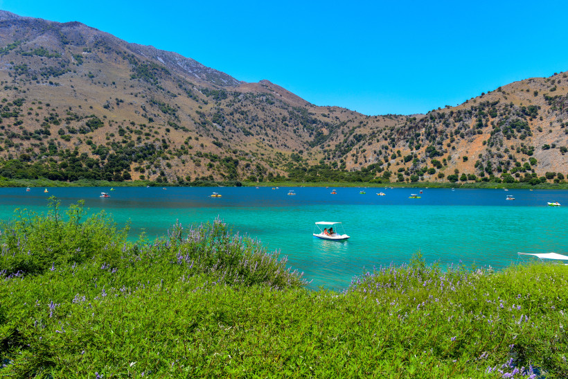 Kournas-See mit türkisfarbenem Wasser, Tretbooten und Bergen im Hintergrund