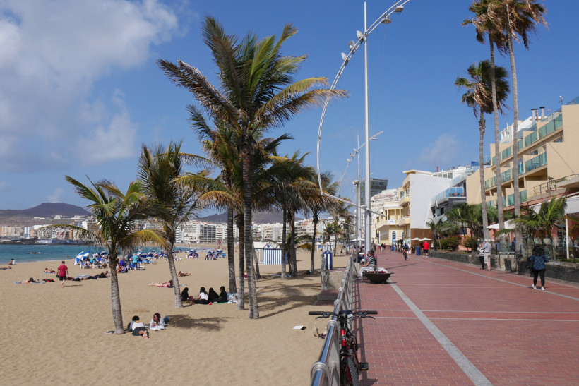 Strandpromenade in Las Palmas de Gran Canaria mit Palmen, Sandstrand und Stadtbebauung