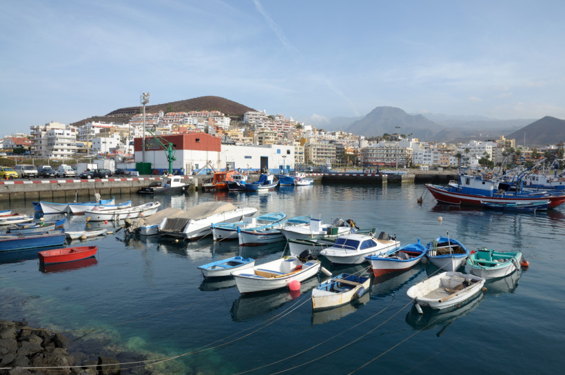 Hafen von Los Cristianos mit kleinen Booten im Vordergrund und Stadtbebauung im Hintergrund