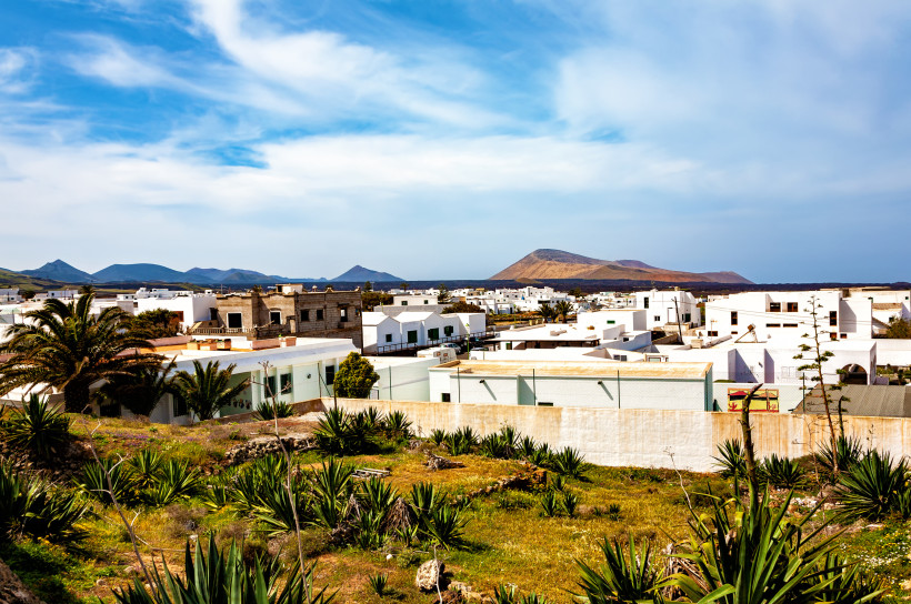 Mancha Blanca auf Lanzarote – Weiß getünchte Häuser vor Vulkankulisse Blick auf Mancha Blanca mit weißen Häusern, grünen Gärten und der Vulkanlandschaft des Timanfaya im Hintergrund auf Lanzarote.