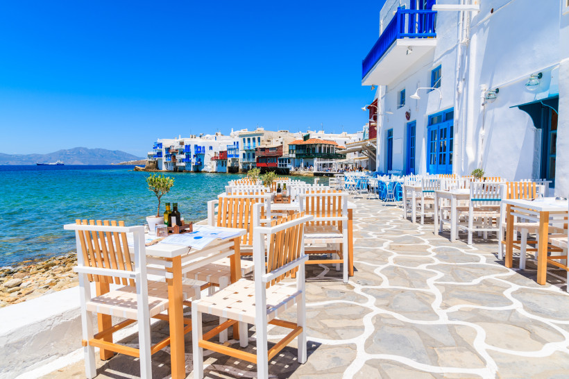 Mykonos - Mykonos-Stadt Strandrestaurant mit weißen Stühlen und Tischen direkt am Wasser im Viertel Little Venice auf Mykonos, Griechenland