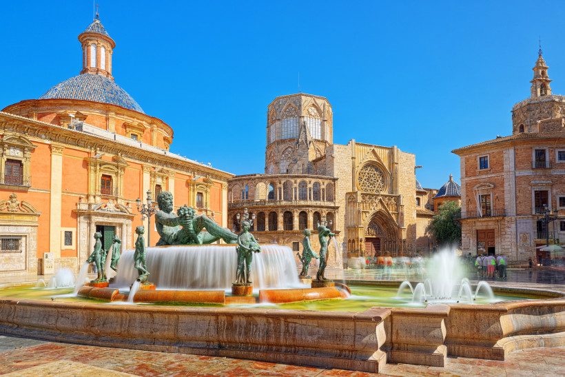 Brunnen mit Skulpturen auf dem Plaza de la Virgen in Valencia, im Hintergrund Kathedralfassade und Kuppelbau