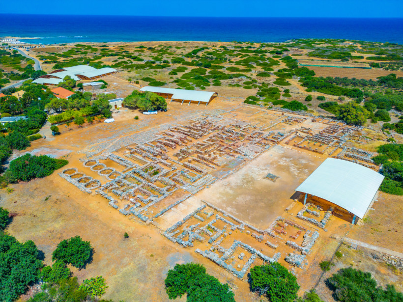 Palast von Malia – Luftaufnahme der archäologischen Ausgrabungsstätte Luftaufnahme der Ausgrabungsstätte des Palasts von Malia mit freigelegten Grundmauern und Schutzdächern nahe der Küste